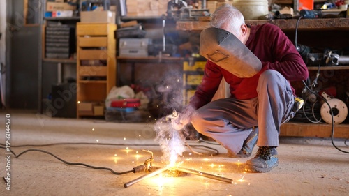 Senior artisan welding metal in a workshop