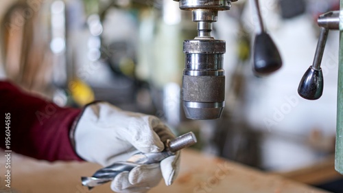 Photography Person changing drill bit on a machine press in workshop