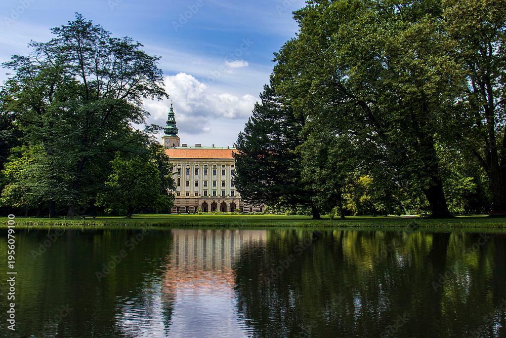 Obraz premium Kromeriz Archbishop's Palace reflecting on the calm surface of a lake in the castle garden. UNESCO historic architecture surrounded by mature trees in a summer park, idyllic