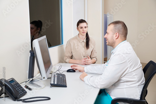 Bild auf Leinwand Young male doctor examining and consulting young female patient in hospital clinic