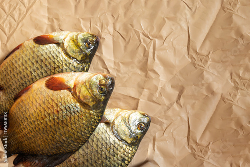 three fresh crucians on wrapping paper from the store.