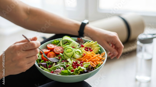 Person eating healthy vegetable salad bowl meal feeling relaxed after fitness workout enjoying wellness diet lifestyle with fresh green tomato carrot cucumber and water bottle nearby