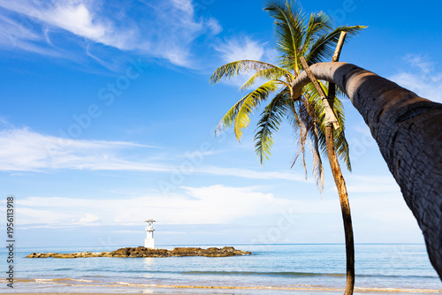 view of the coconut-lined beach at the lighthouse in Khao Lang, Thailand, against a beautiful sky.