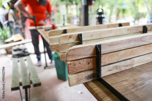 Focused carpenter at workshop assembling wooden bench with metal bracket. close up detail of craftsmanship, woodwork, and furniture making in rustic outdoor setting