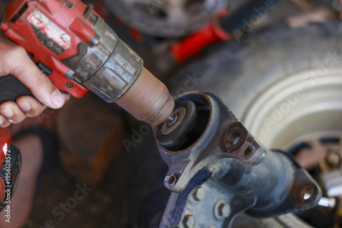 Focused mechanic using power tool for car repair and maintenance work. man hand holding drill during an auto service in garage. Close up of action