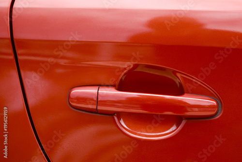 Close up detail of vibrant red car door handle on modern automobile. glossy paint and sleek body panel create powerful and shiny abstract transportation background