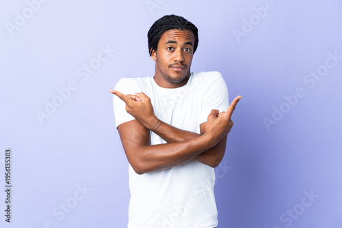 Bild auf Leinwand Young African American man with braids man isolated on purple background pointin