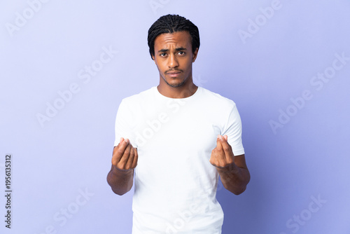 Young African American man with braids man isolated on purple background making money gesture but is ruined