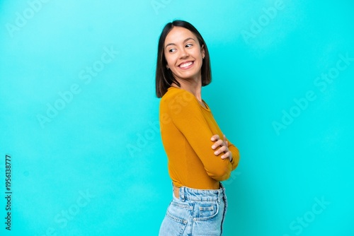 Young caucasian woman isolated on blue background looking to the side and smiling