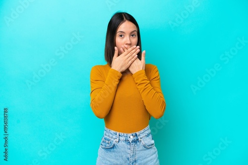 Young caucasian woman isolated on blue background covering mouth with hands