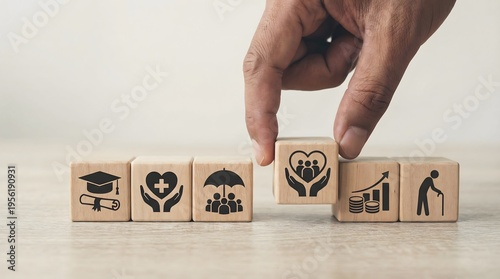 Hand carefully placing a wooden block with a family care icon into a structured row depicting various essential life insurance and social security concepts.