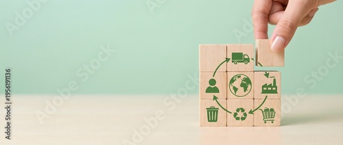 Hand places a wooden block with a connecting arrow onto a system of circular economy icons, representing sustainable resource management.