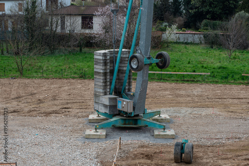 Tower crane lifting construction materials on building site against blue sky, urban development concept
