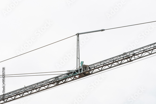 Tower crane lifting construction materials on building site against blue sky, urban development concept