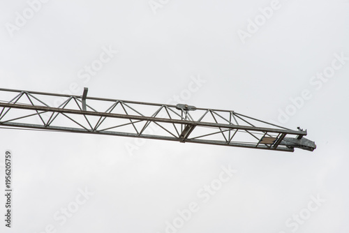 Tower crane lifting construction materials on building site against blue sky, urban development concept
