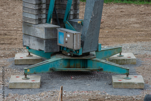 Tower crane lifting construction materials on building site against blue sky, urban development concept
