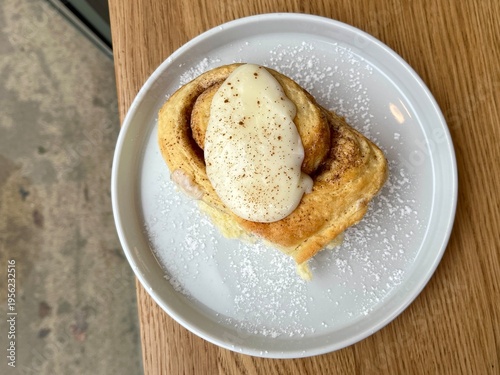 Delicious cinnamon bun with creamy frosting, bite taken, showing fluffy interior texture.