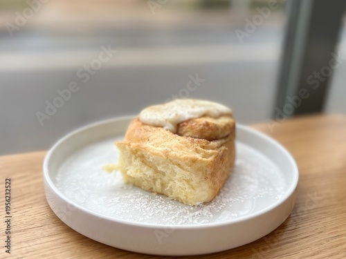 Soft and airy cinnamon roll with icing, freshly baked pastry on a wooden table, warm comfort food concept