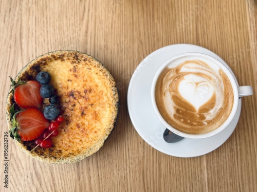 Classic French dessert crème brûlée with strawberries and blueberries, paired with coffee, soft focus background, elegant breakfast or dessert concept.