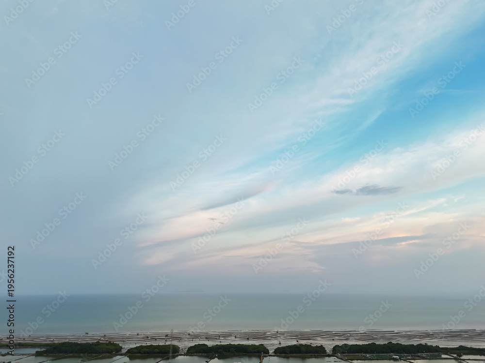 Obraz premium Aerial coastal horizon with soft pastel sky above calm sea and shoreline vegetation