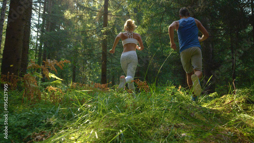 LOW ANGLE: Sporty couple training in the scenic woods for a trail running race.