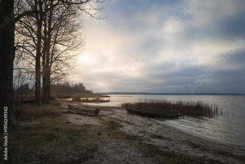 Old rural wooden, fishing boat is moored on the shore of a lake. A gloomy windy day