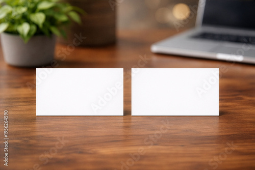 木目デスクの上に並べた白い名刺カード2枚のモックアップ