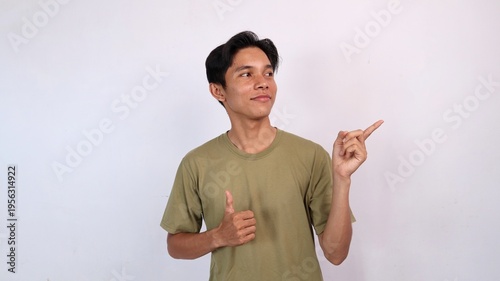 young asian man smiling ok gesture, pointing and looking to the side