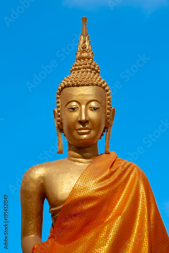 A statue of a golden Buddha with a blue sky background near the Great Stupa in Vientiane, Laos