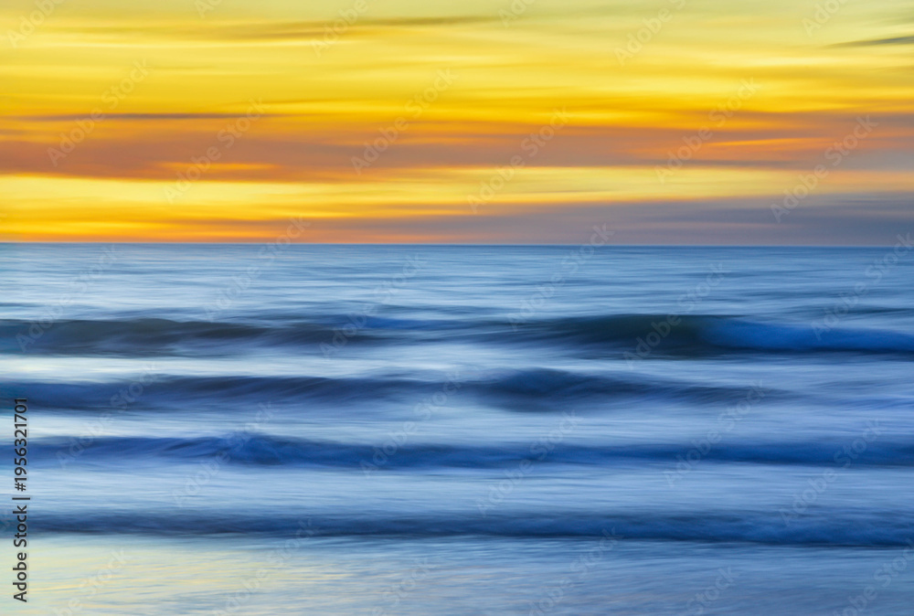 Fototapeta premium Long exposure photography panning of ocean waves breaking at sunset.