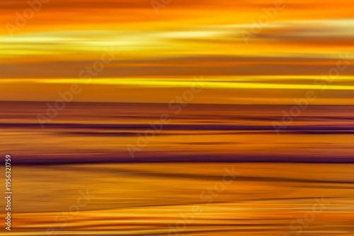 Long exposure photography panning of ocean waves breaking at sunset.