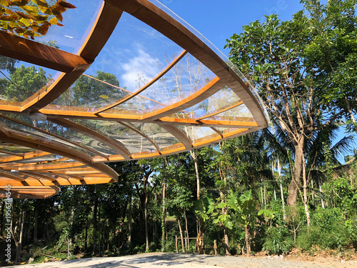 glass canopy covers the facade of a building located in a forested nature park.