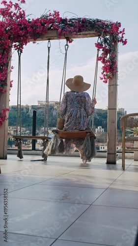 Woman on swing with panoramic view of Athens skyline and ancient Acropolis temple