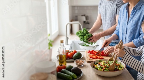 Family cooking healthy salad together in modern kitchen parents and child preparing fresh vegetables organic food lifestyle teamwork wellness home meal nutrition happiness togetherness daily routine