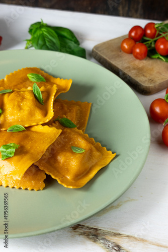 Homemade ravioli with cherry tomatoes and basil on rustic table, Italian fresh pasta
