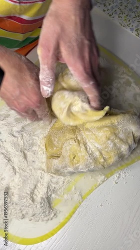 Kneading dough on a light table on a transparent board with flour on it, top view, vertical shot, cooking process