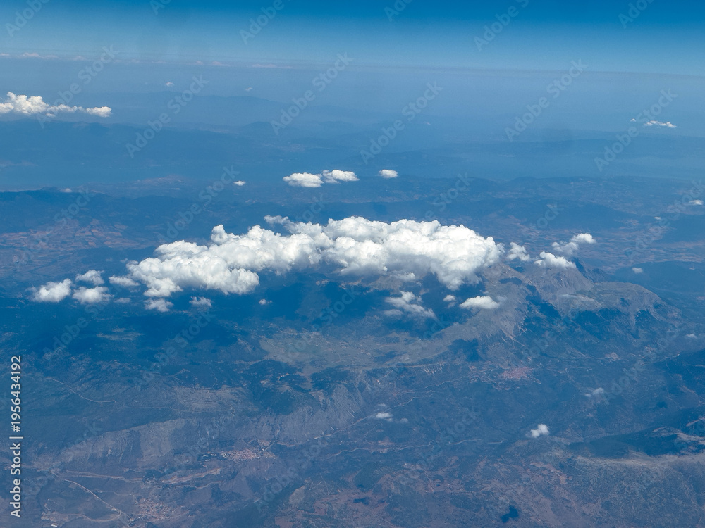 Fototapeta premium Aerial view of mountain range with scattered clouds under clear summer sky in central Greece