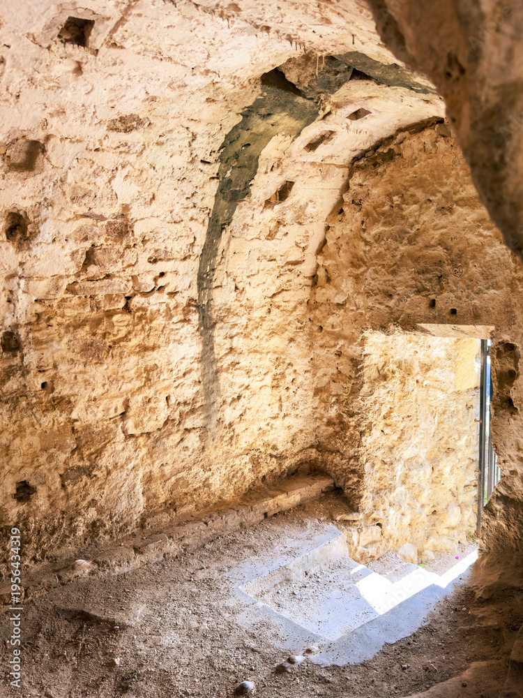 Fototapeta premium Stone vault interior inside the Old Fortress in Corfu Old Town, Greece. Rough masonry, arched ceiling and doorway light