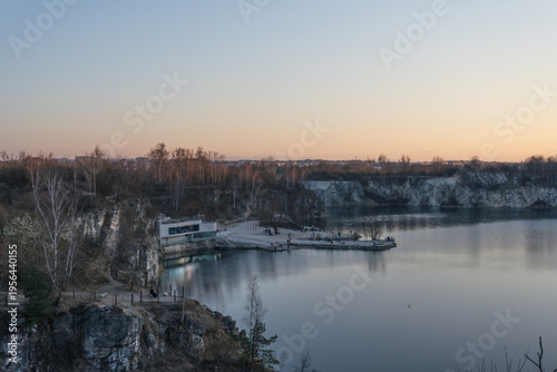 Scenic quarry lake with modern building and rocky cliffs at sunset