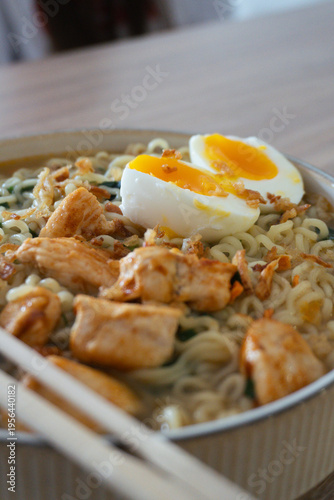 Delicious chicken ramen with soft boiled egg and crispy fried onions, served in a bowl with chopsticks