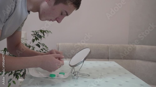 A young guy puts on contact lenses, The process of putting on contact lenses at home