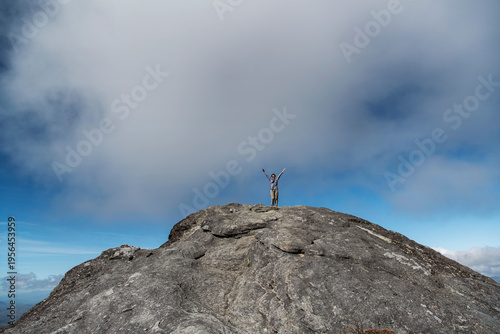 A triumphant woman on top of Grandfather mountain in North Carolina