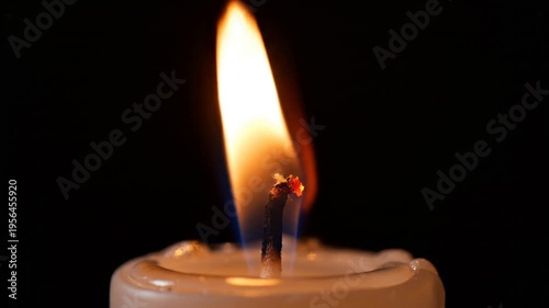 Macro shot of a single candle flame flickering against a black background