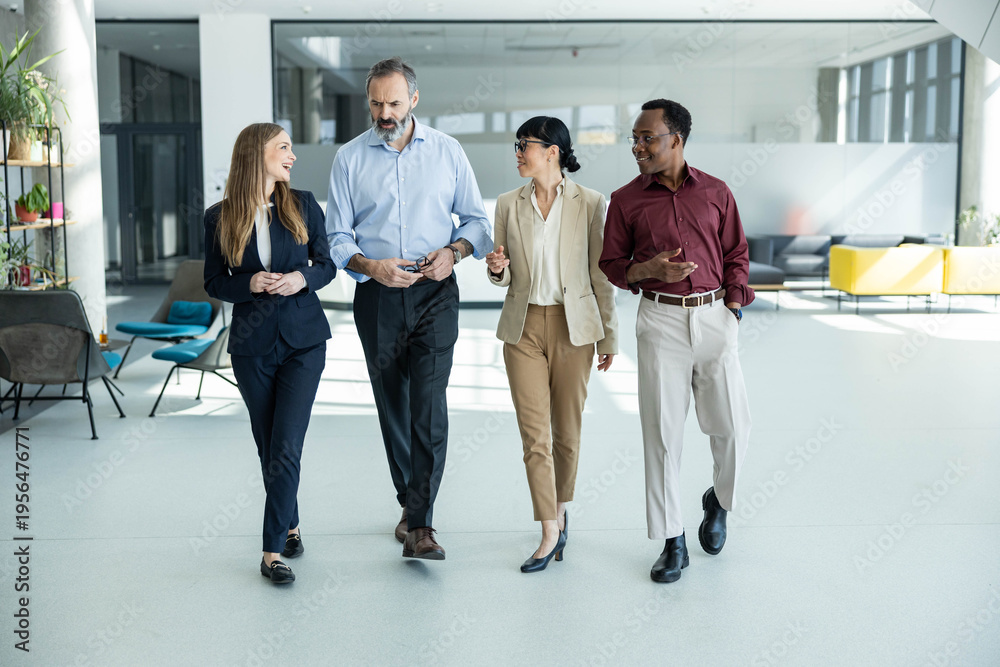 Fototapeta premium Diverse group of business professionals walking and having a discussion in a modern corporate office, symbolizing teamwork and communication