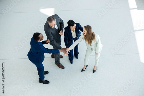 Canvas-taulu Four diverse businesspeople stacking hands, symbolizing unity, partnership, and