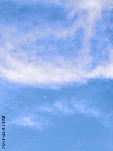 Thin Crescent Moon in Soft Blue Cloudy Sky