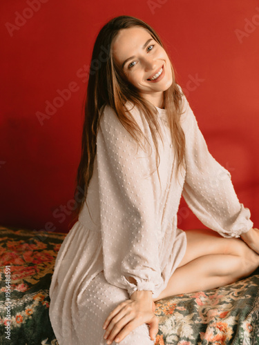 Smiling young woman on red background, beauty boudoir concept
