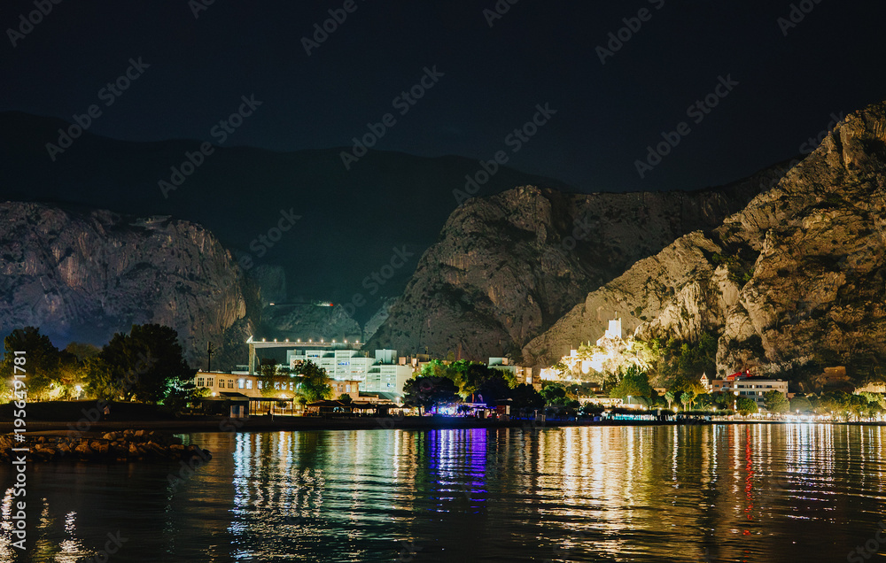 Obraz premium Illuminated Mirabella fortress and mountain cliffs at night in Omis.