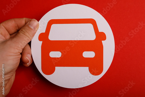 Free Download Close up shot of a hand holding a car symbol cut out against a vivid red backdrop. Perfect for automotive themes. - GFXLoad