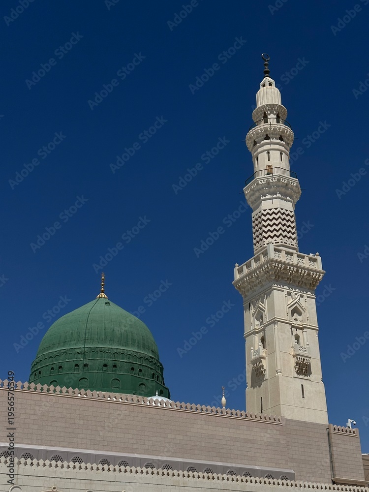 Obraz premium Masjid al-Nabawi (the Prophet’s Mosque) in Medina, Saudi Arabia, one of Islam’s holiest sites, featuring its iconic green dome, expansive courtyards, and elegant minarets, visited by millions